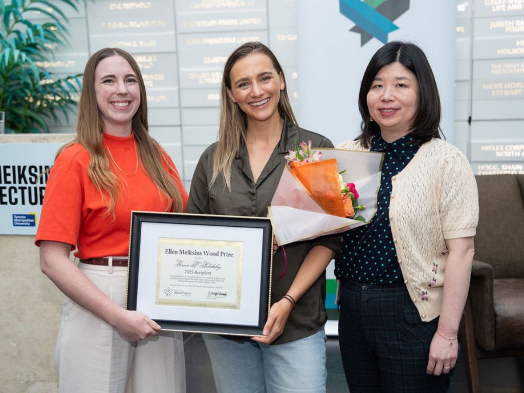 Jen Hassum, Grace Blakeley and Amy Peng standing together, smiling, with Grace holding a certificate reading Ellen Meiksins Wood Prize.